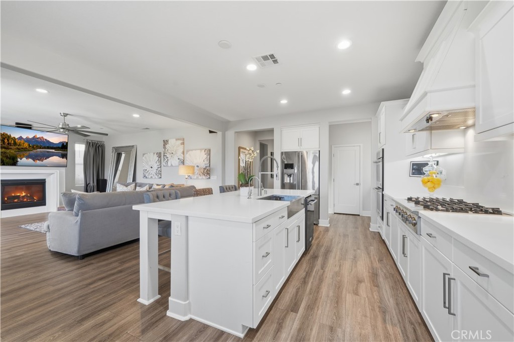 346 Ventasso Way Fallbrook, CA 92028 - Photo 12 of 56 a large white kitchen with wooden floor and stainless steel appliances