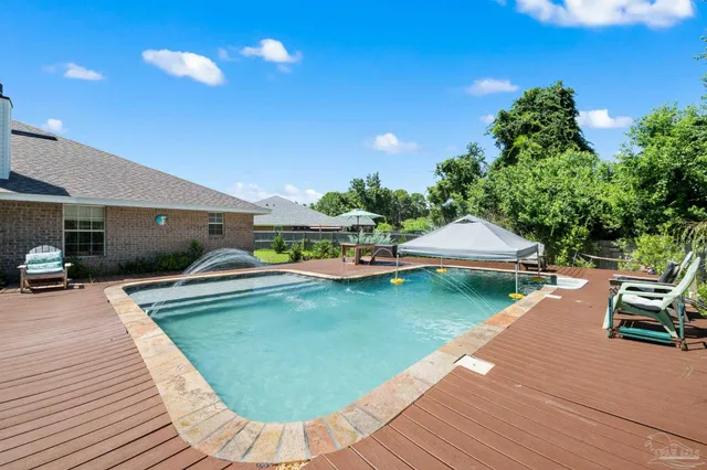 a view of a swimming pool with a patio and a yard