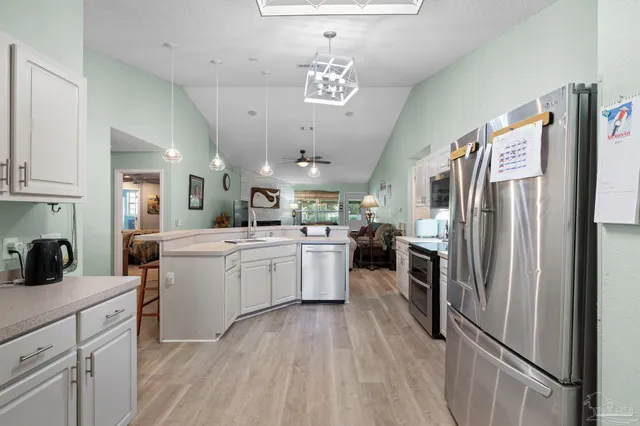 a kitchen with kitchen island a counter top space a sink stainless steel appliances and cabinets