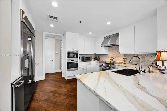 a kitchen with stainless steel appliances a sink a stove a dining table and chairs