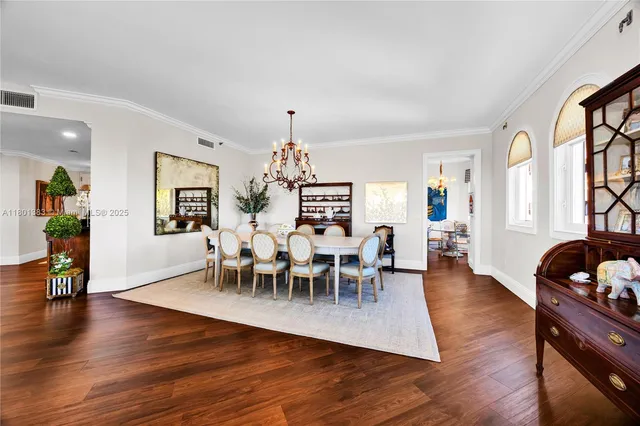 a dining room with wooden floor a chandelier a wooden table and chairs