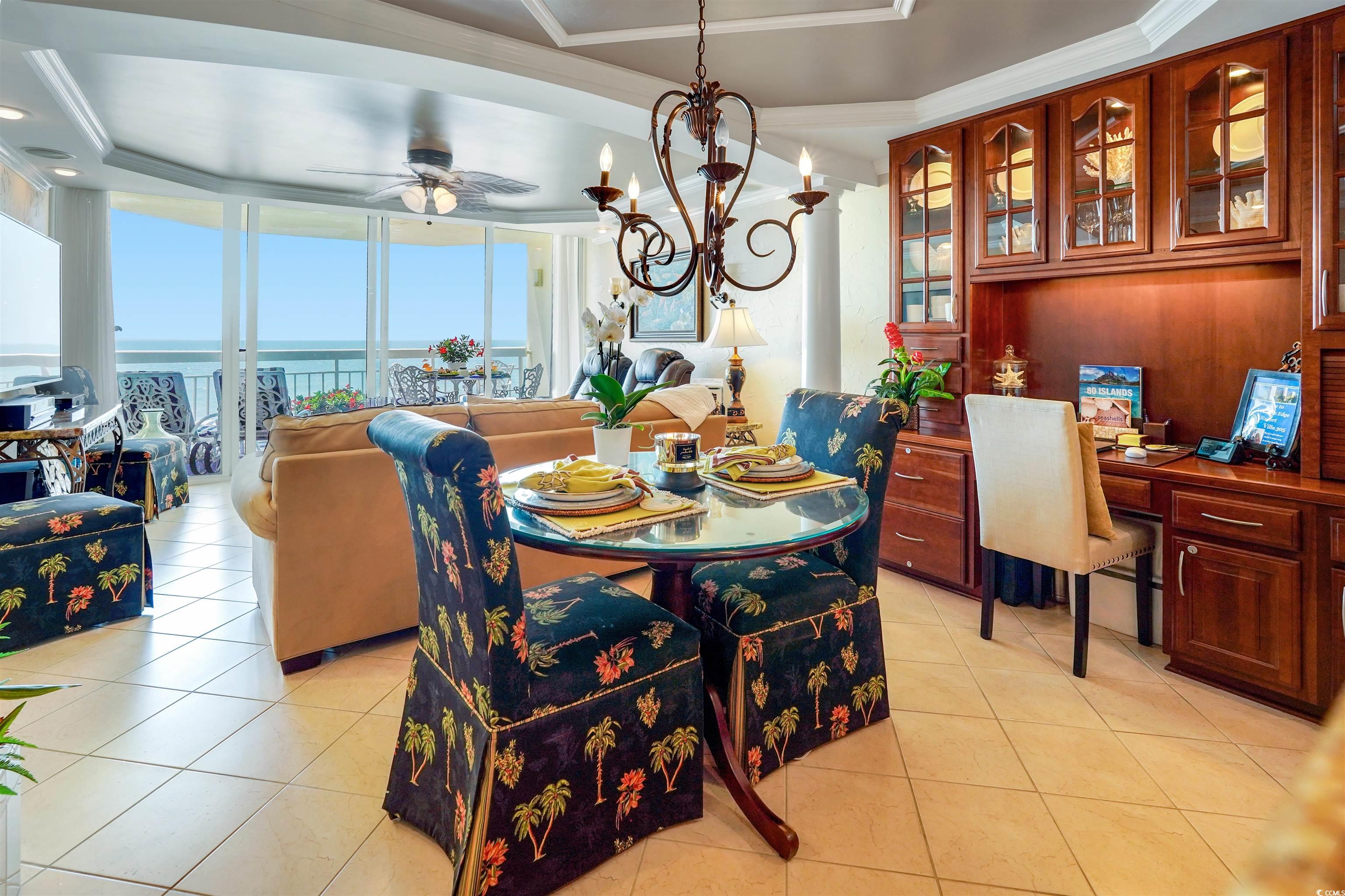 1012 North Waccamaw Drive, Unit 305 Murrells Inlet, SC 29576 - Photo 13 of 38 Dining room featuring light tile patterned flooring, ceiling fan, a raised ceiling, crown molding, and a chandelier