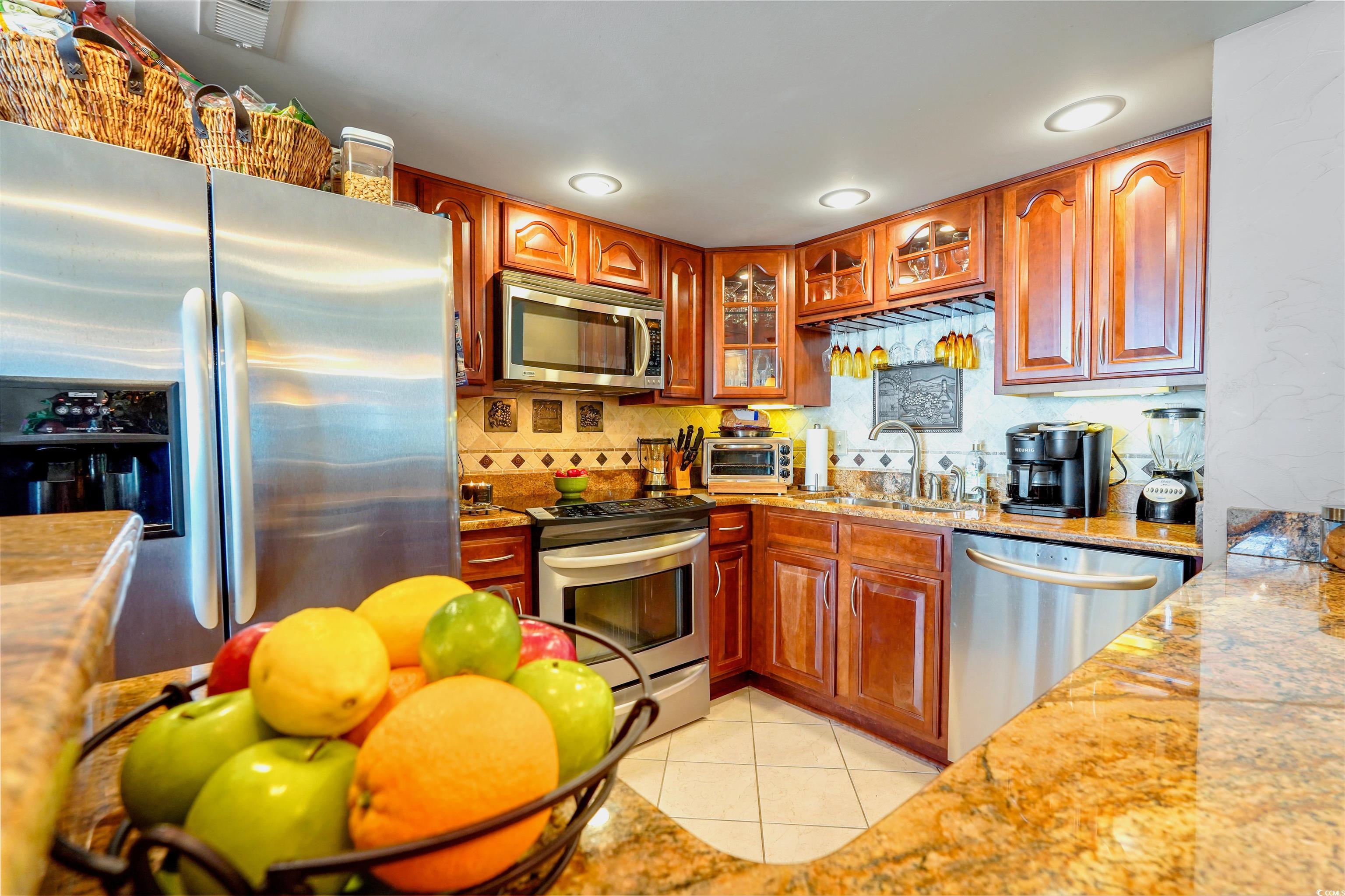 1012 North Waccamaw Drive, Unit 305 Murrells Inlet, SC 29576 - Photo 15 of 38 Kitchen with stainless steel appliances, a sink, light tile patterned floors, glass insert cabinets, and decorative backsplash