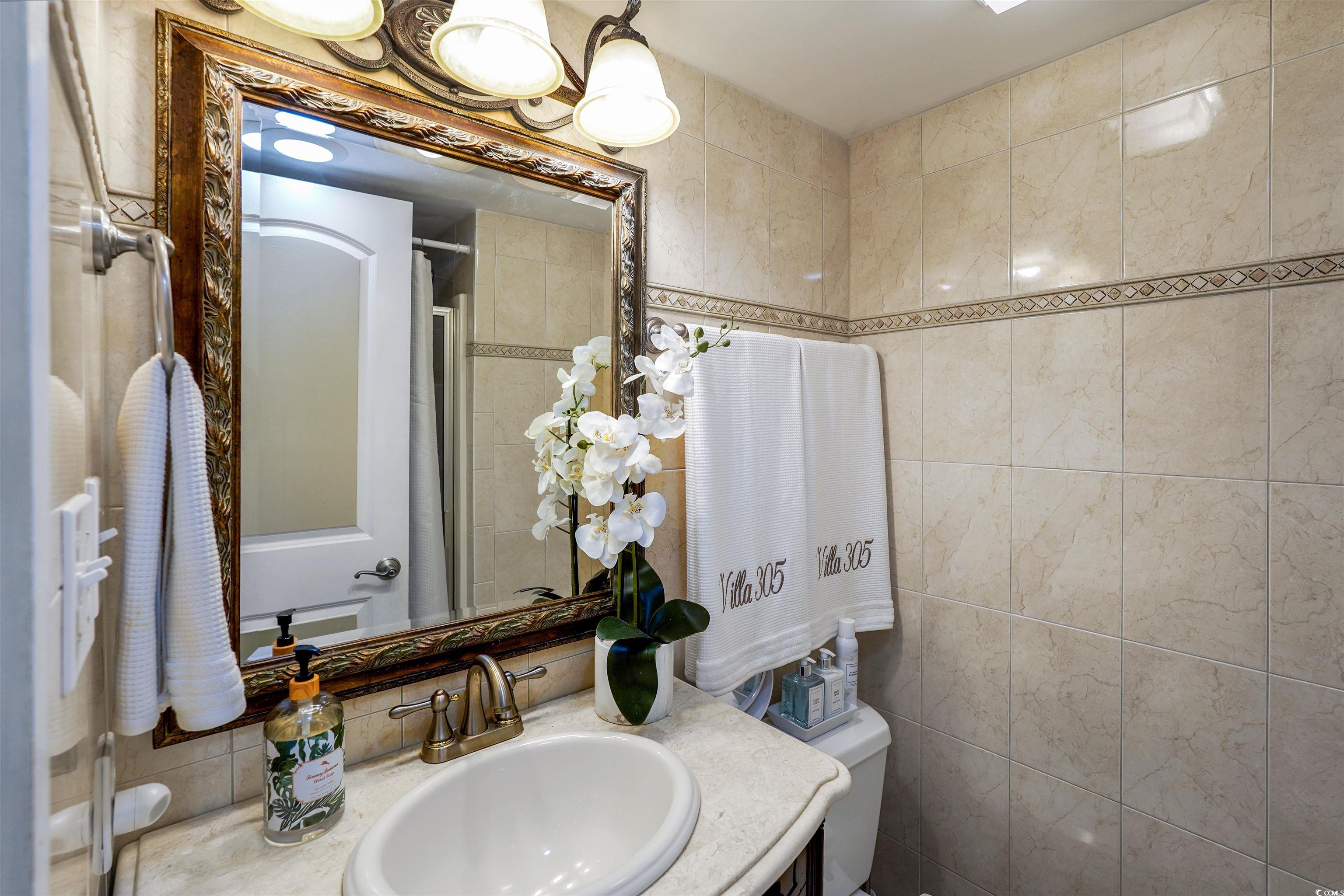 1012 North Waccamaw Drive, Unit 305 Murrells Inlet, SC 29576 - Photo 22 of 38 Bathroom featuring toilet, vanity, tile walls, and a shower
