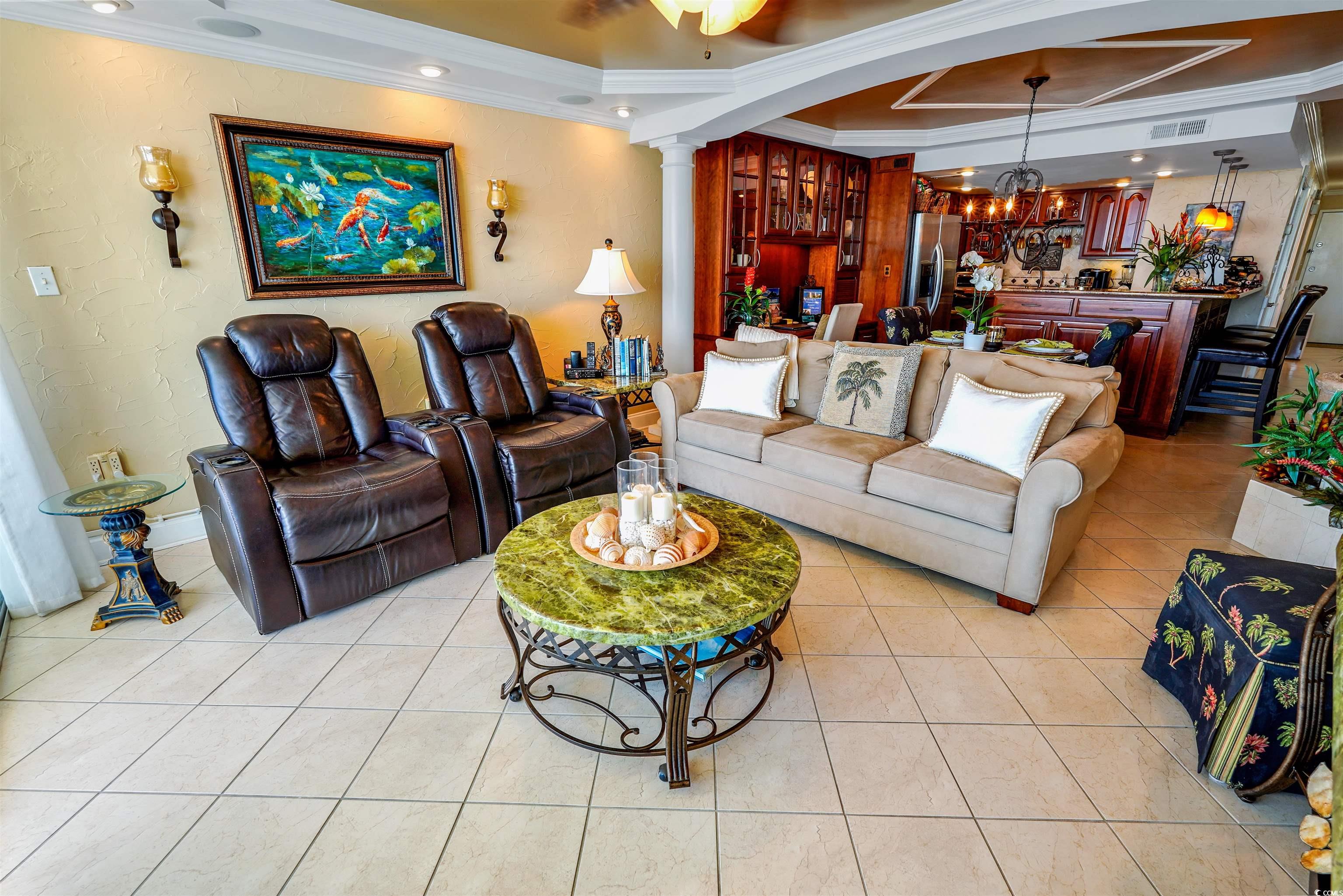 1012 North Waccamaw Drive, Unit 305 Murrells Inlet, SC 29576 - Photo 7 of 38 Living area featuring crown molding, a chandelier, decorative columns, a raised ceiling, and light tile patterned floors