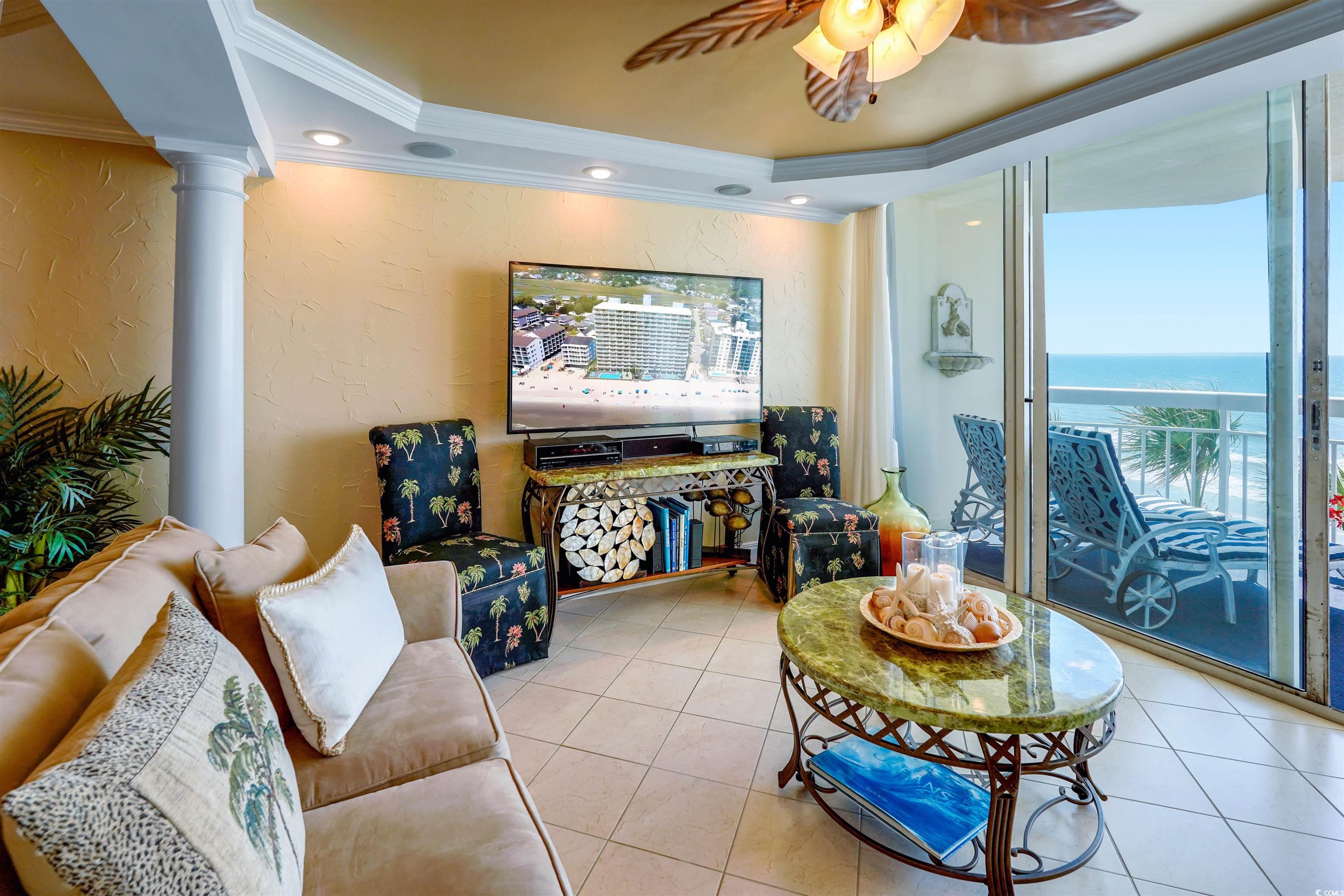 1012 North Waccamaw Drive, Unit 305 Murrells Inlet, SC 29576 - Photo 9 of 38 Tiled living room featuring ornamental molding, a raised ceiling, a textured wall, decorative columns, and ceiling fan