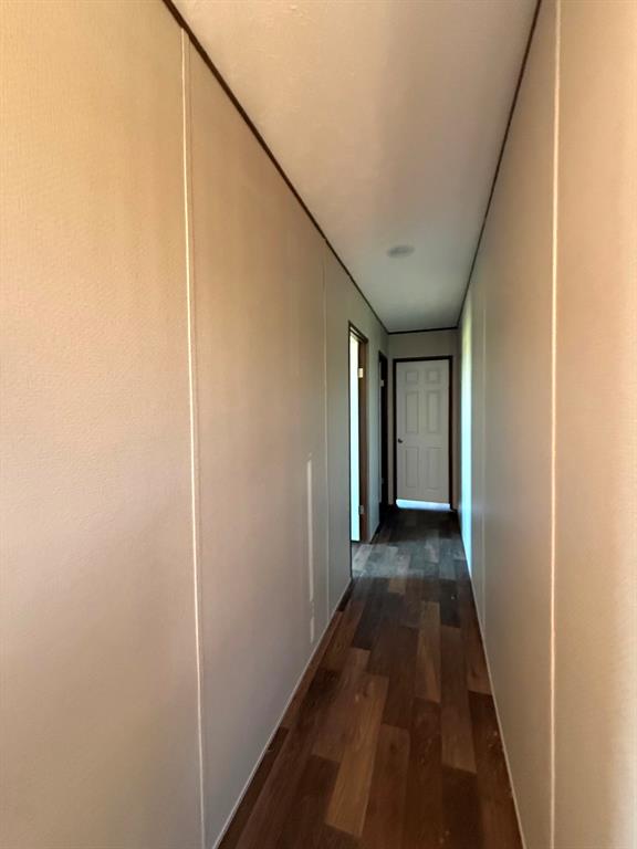 0 Southeast 4060 Road, Unit 25 Kerens, TX 75144 - Photo 11 of 18 Hallway featuring wood-finish flooring, light-toned walls with vertical paneling, and a white paneled door