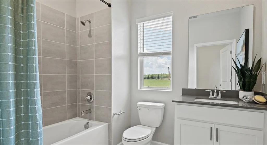 4246 St Thomas Way Kissimmee, FL 34758 - Photo 14 of 16 a bathroom with a granite countertop sink a toilet a mirror a vanity and shower