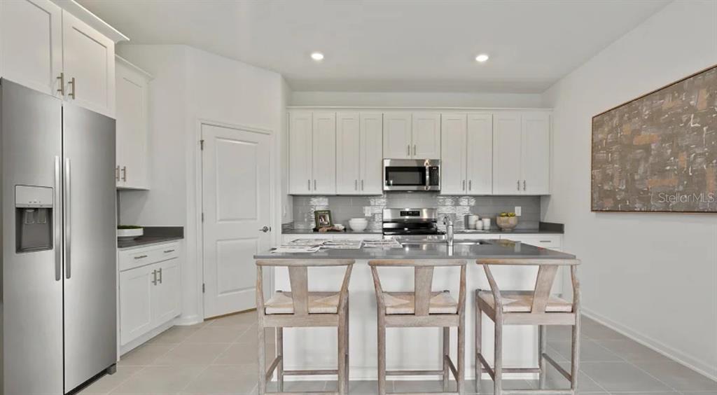 4246 St Thomas Way Kissimmee, FL 34758 - Photo 3 of 16 a kitchen with white cabinets and stainless steel appliances