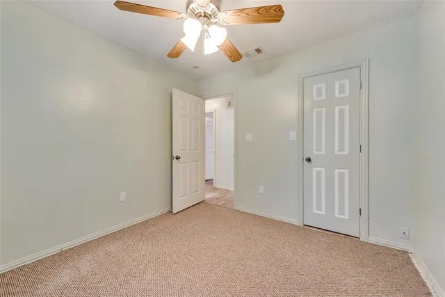 an empty room with a chandelier fan and closet area