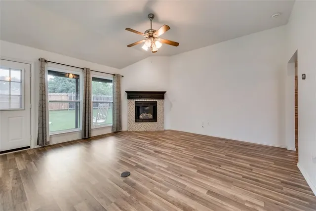 a view of an empty room with a window and wooden floor