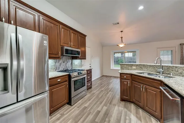 a kitchen with stainless steel appliances granite countertop a stove refrigerator sink and microwave