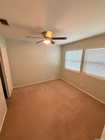 an empty room with a window and a fan