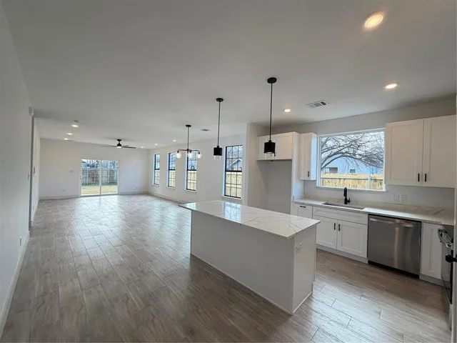 a large kitchen with stainless steel appliances kitchen island a large counter top and a wooden floors