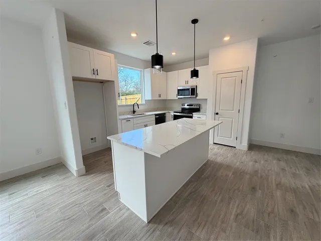 a large kitchen with stainless steel appliances a large counter top a sink and a refrigerator