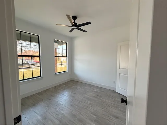 a view of empty room with wooden floor and fan