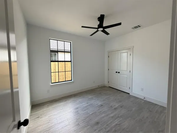 a view of empty room with wooden floor and fan