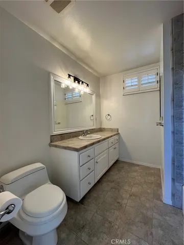 a bathroom with a granite countertop toilet sink and mirror
