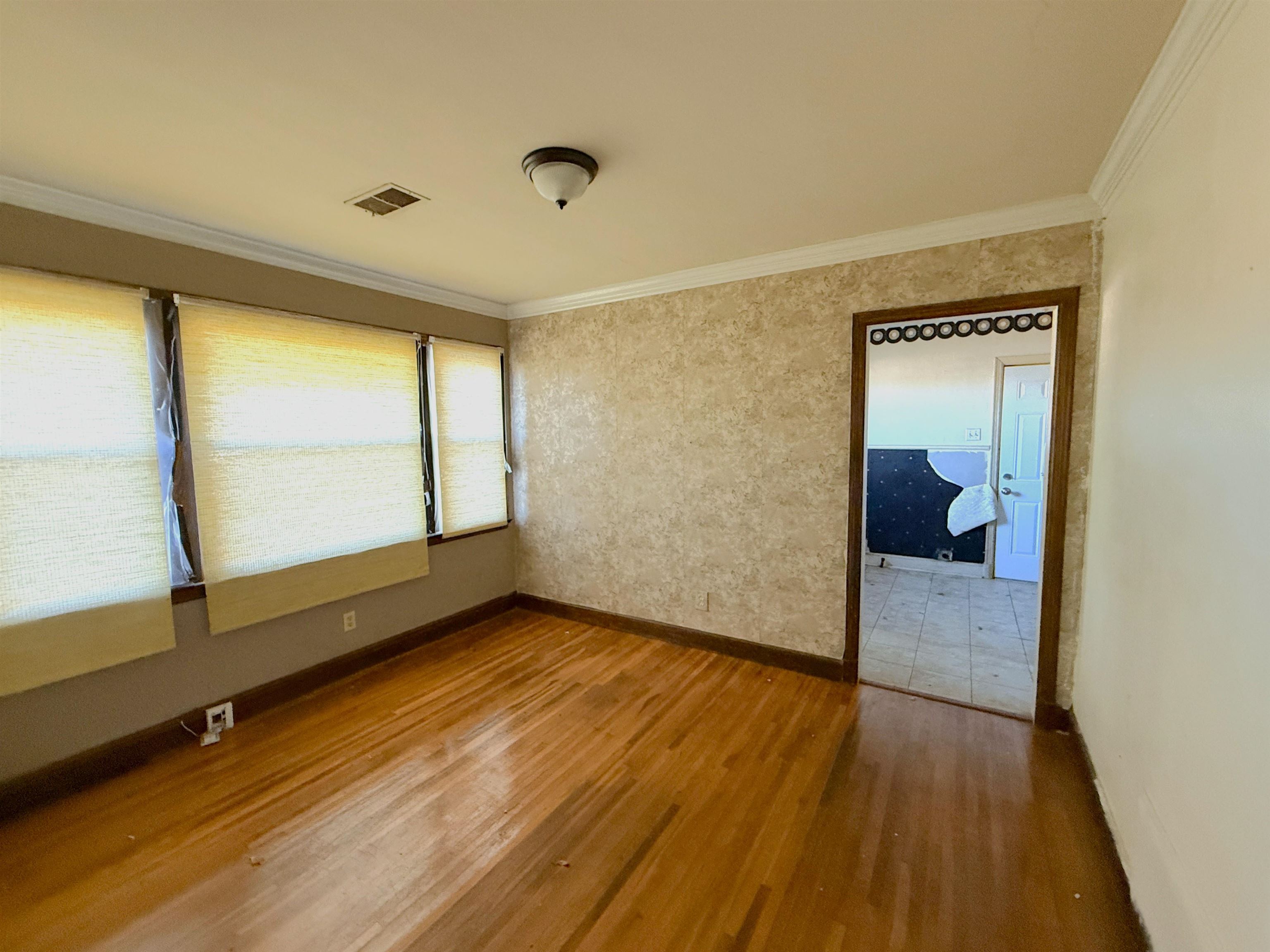 1229 Marlin Road Memphis, TN 38116 - Photo 3 of 20 Spare room with wallpapered walls, crown molding, and wood finished floors