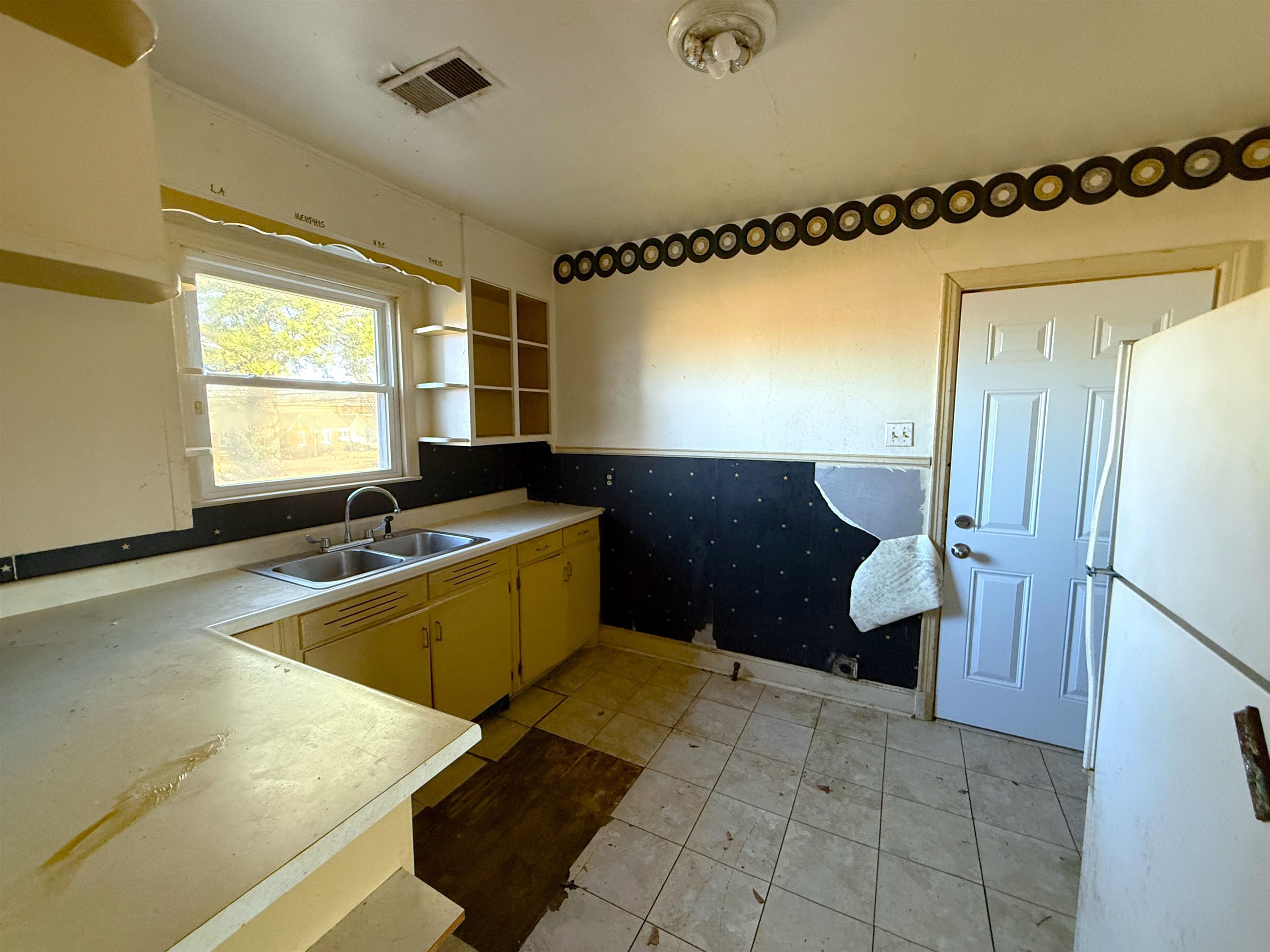1229 Marlin Road Memphis, TN 38116 - Photo 4 of 20 Kitchen featuring light countertops, freestanding refrigerator, open shelves, and a wainscoted wall