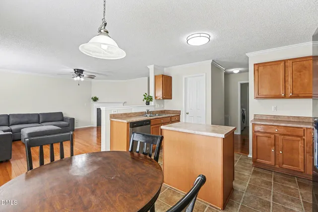 a kitchen with stainless steel appliances granite countertop a stove top oven a refrigerator a sink dishwasher a dining table and chairs with wooden floor