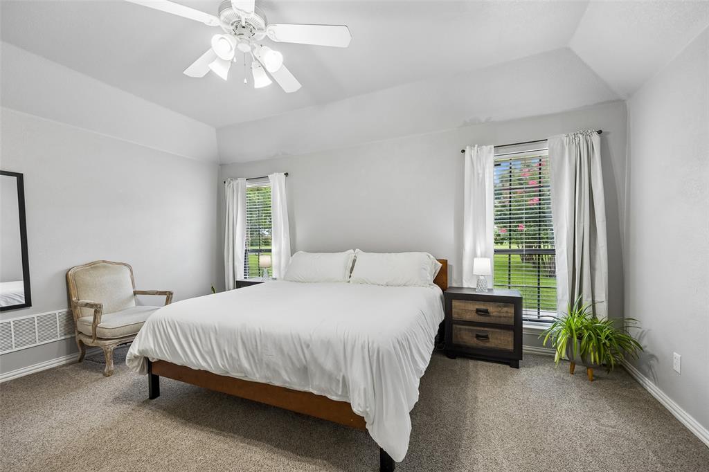 11211 Emerald Ranch Lane Forney, TX 75126 - Photo 22 of 35 Primary Carpeted bedroom featuring a tray ceiling, ceiling fan with integrated lighting, and two windows with blinds