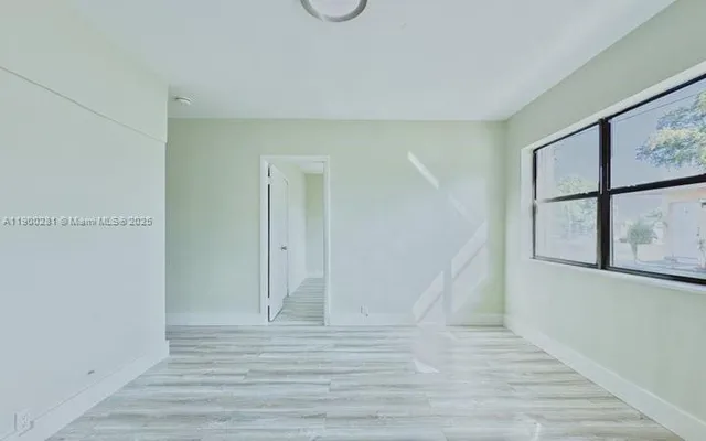 a view of an empty room with wooden floor and windows