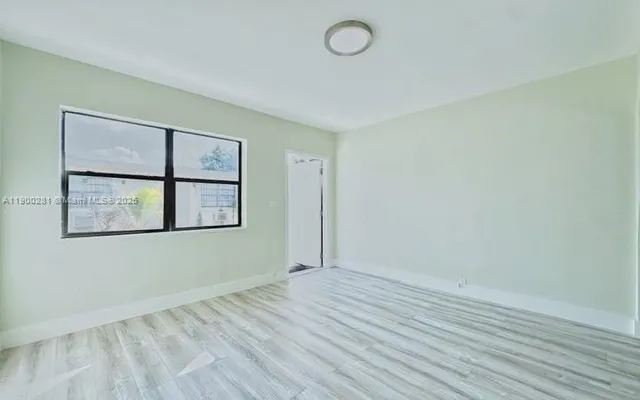 an empty room with wooden floor and window
