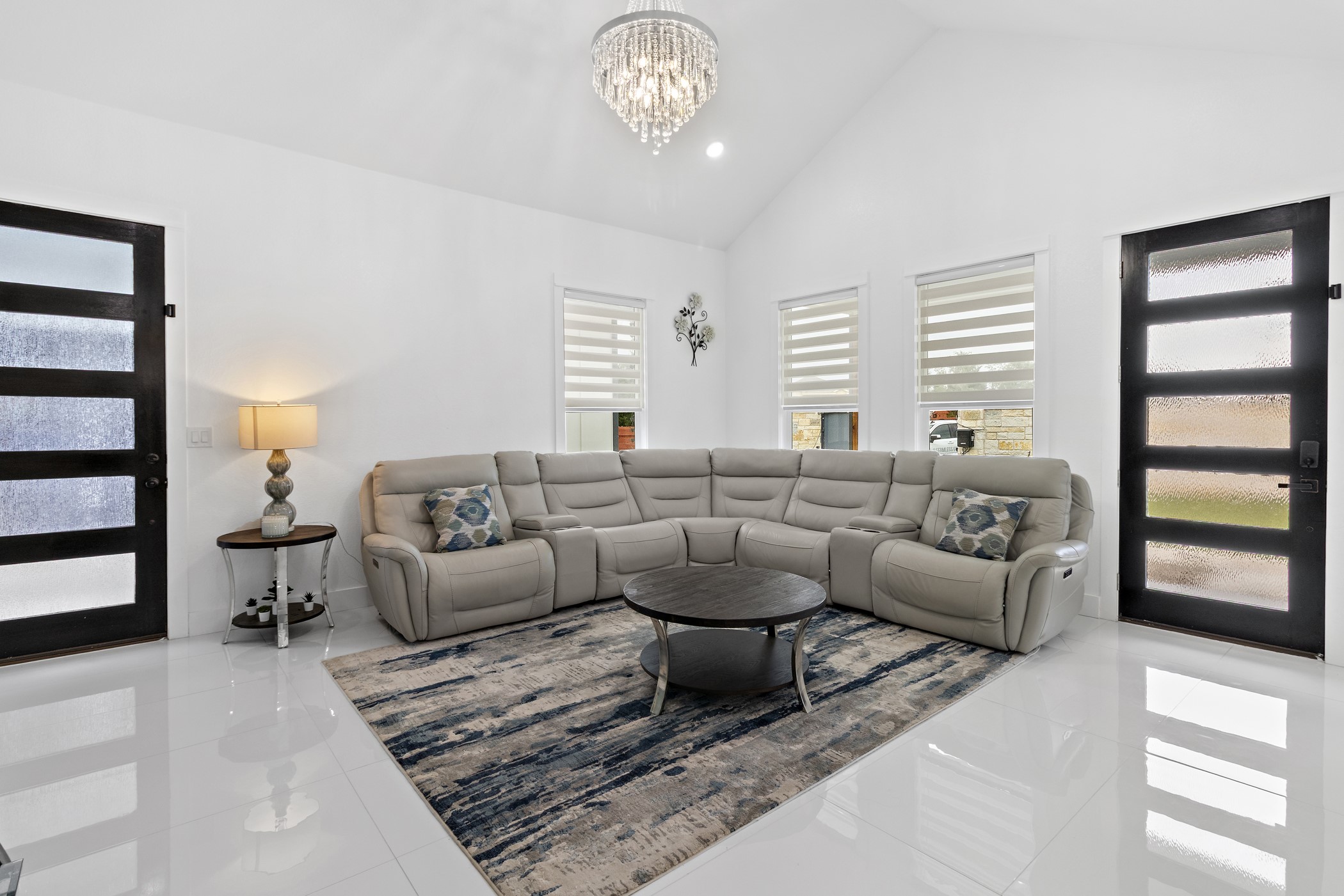 123 Zacate Street Elgin, TX 78621 - Photo 22 of 33 Vaulted ceiling living area featuring high-gloss tile flooring, a prominent chandelier, and dark-framed doors with frosted glass panels