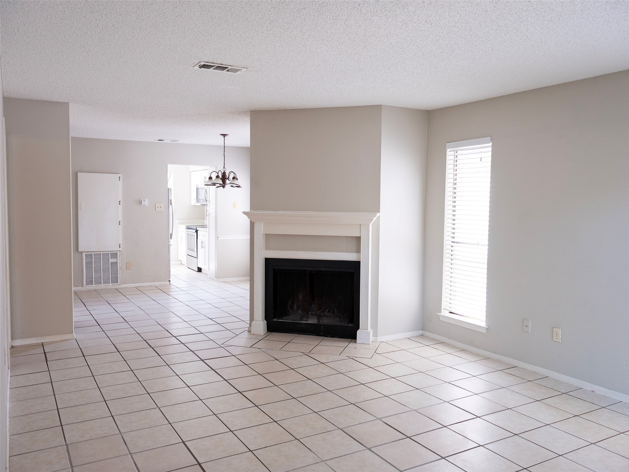 1903 West Loop, Unit B Austin, TX 78758 - Photo 3 of 15 Unfurnished living room featuring a wealth of natural light, visible vents, and a chandelier