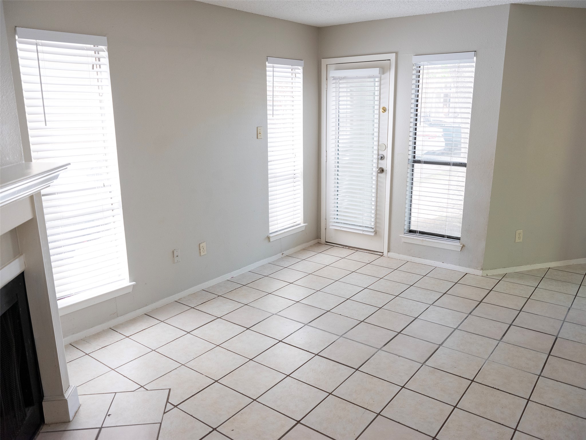1903 West Loop, Unit B Austin, TX 78758 - Photo 5 of 15 Unfurnished living room featuring baseboards, a fireplace, and a textured ceiling