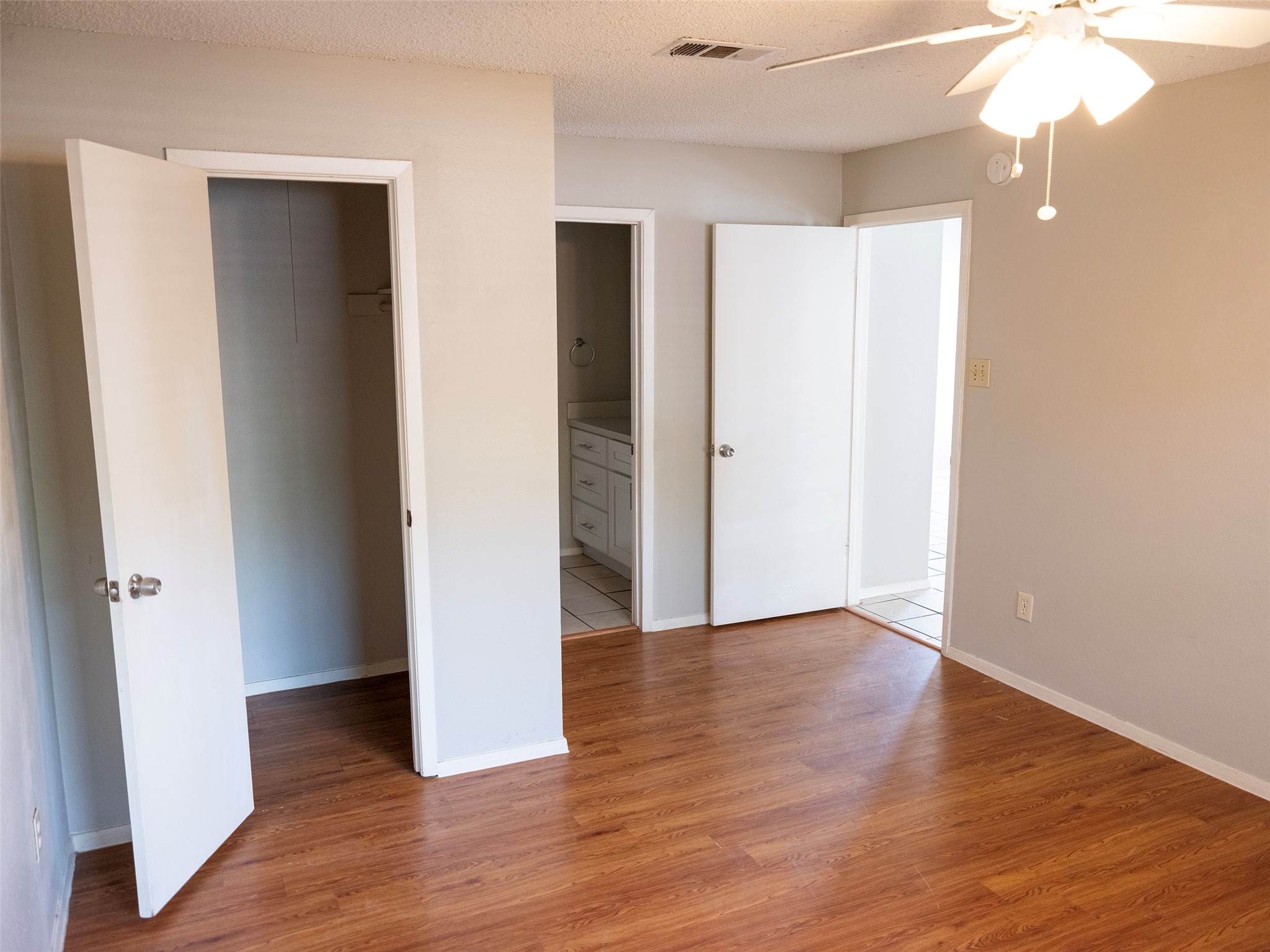 1903 West Loop, Unit B Austin, TX 78758 - Photo 8 of 15 Unfurnished bedroom with a spacious closet, a textured ceiling, visible vents, light wood-style flooring, and a closet