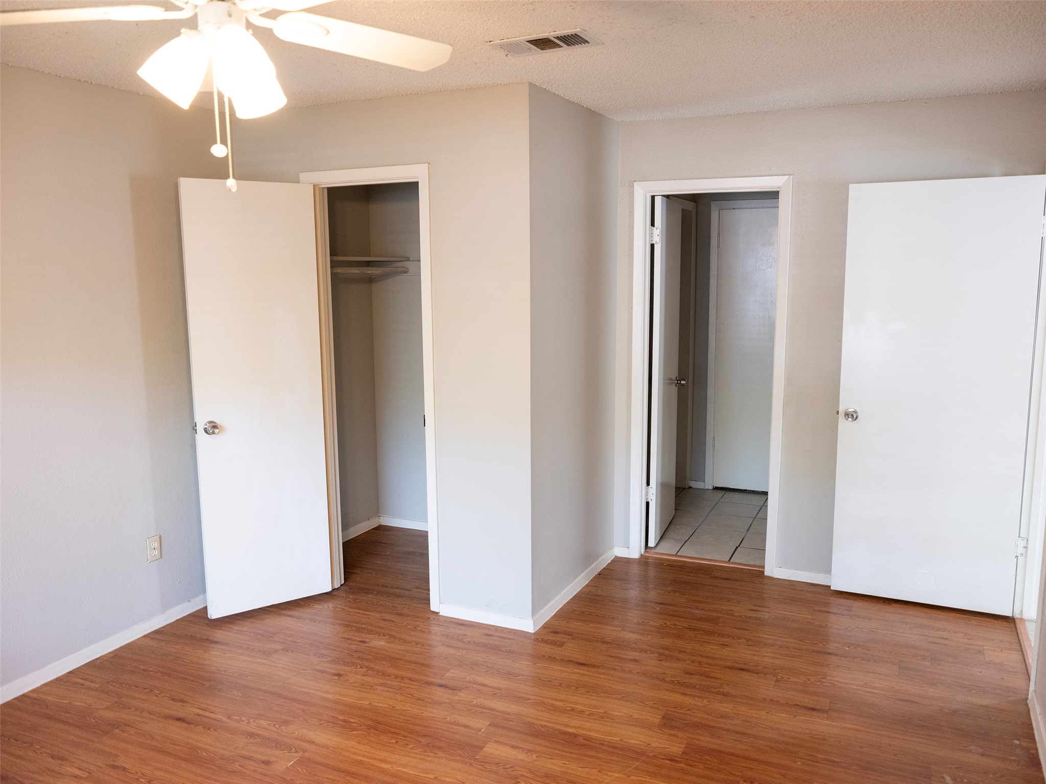 1903 West Loop, Unit B Austin, TX 78758 - Photo 9 of 15 Unfurnished bedroom featuring baseboards, light wood-style floors, a textured ceiling, and visible vents