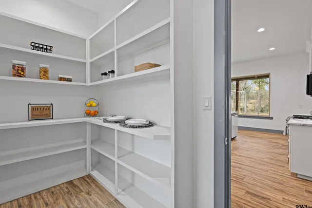 a view of an empty room with wooden floor and a ceiling fan