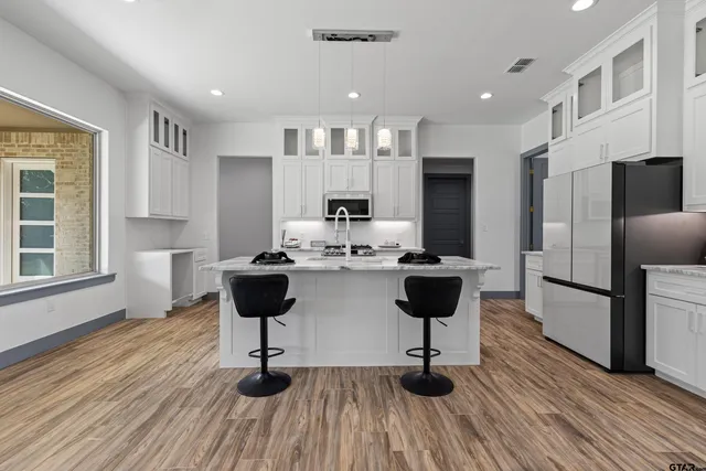 a kitchen with a sink and white cabinets with wooden floor