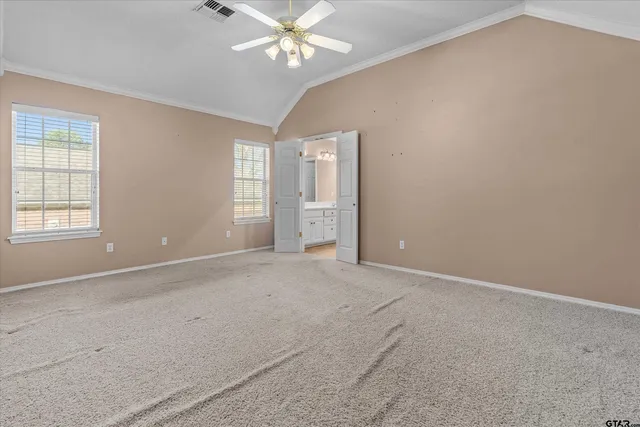 an empty room with chandelier fan and windows