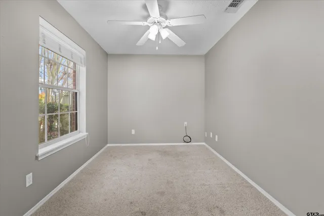 an empty room with windows and fan