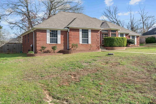 a view of a yard in front of a house with large windows