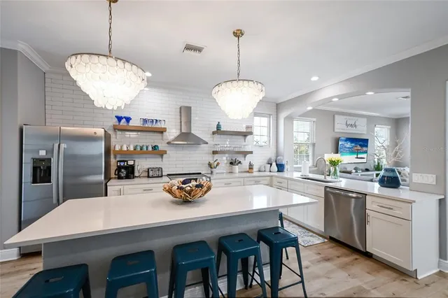 a kitchen with stainless steel appliances a dining table chairs and white cabinets