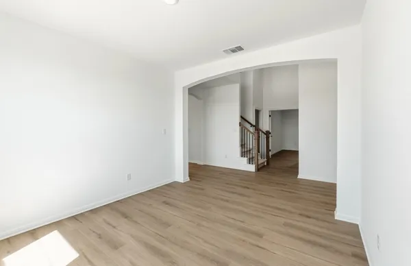 a view of an empty room with window and wooden floor