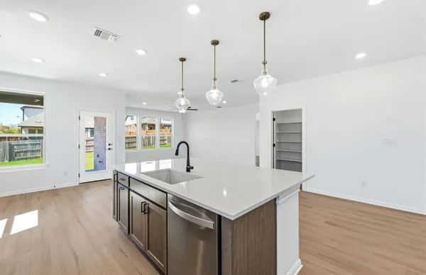 a large kitchen with kitchen island a stove a sink a center island and wooden floor