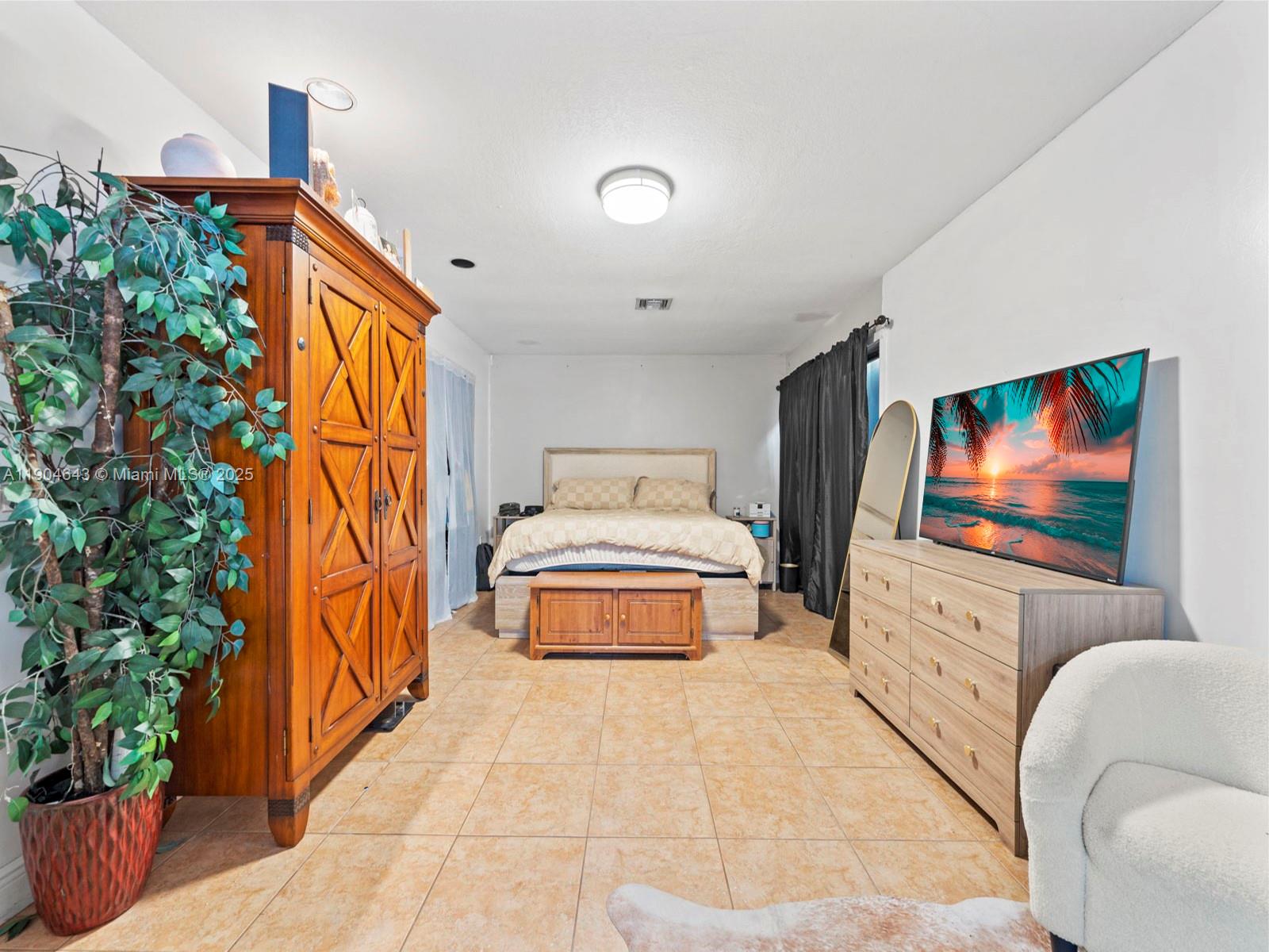 12825 Southwest 107th Terrace Miami, FL 33186 - Photo 12 of 43 a spacious bedroom with a bed and a flat screen tv
