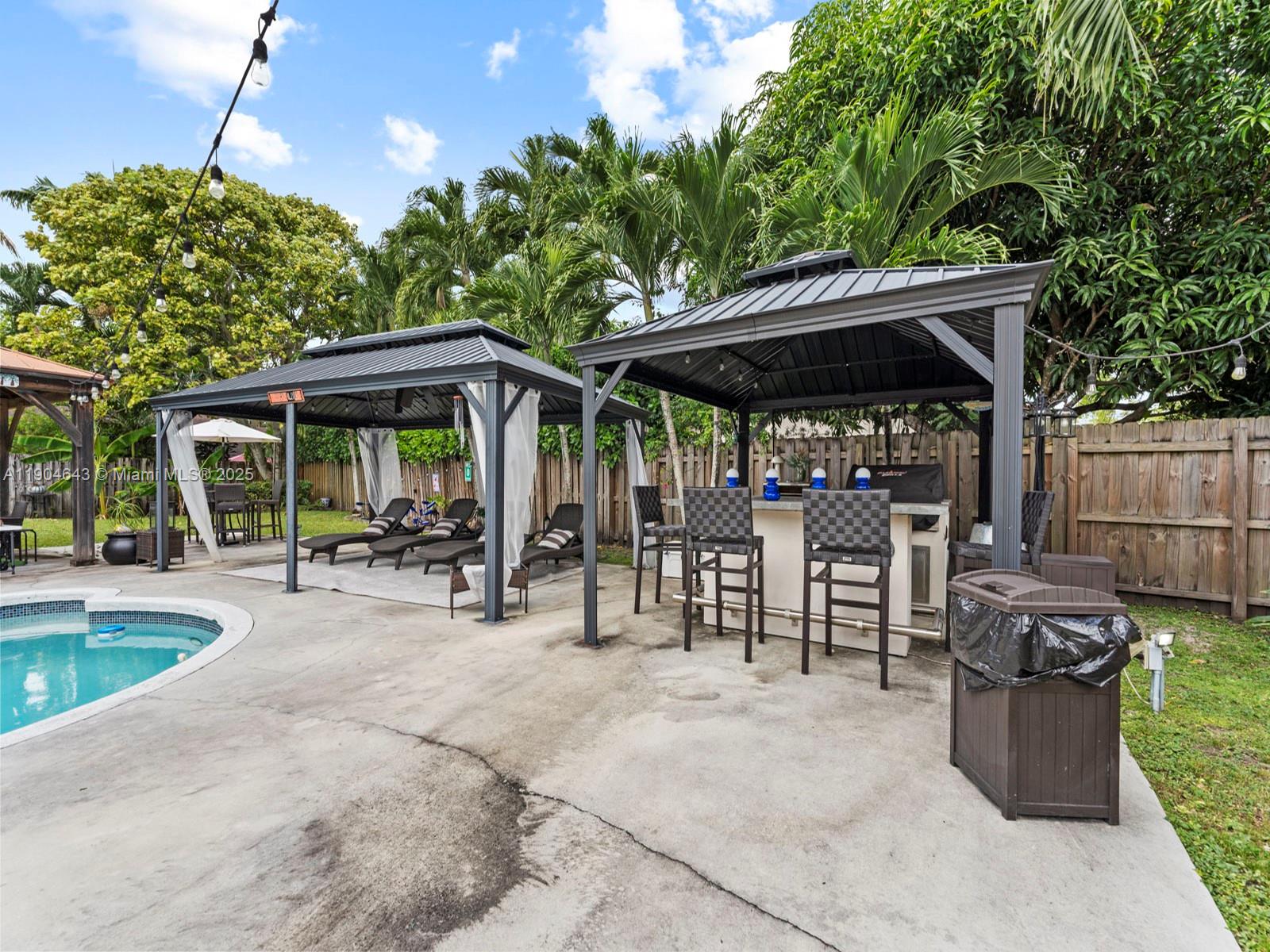 12825 Southwest 107th Terrace Miami, FL 33186 - Photo 37 of 43 a view of a patio with a dining table and chairs under an umbrella with a small yard