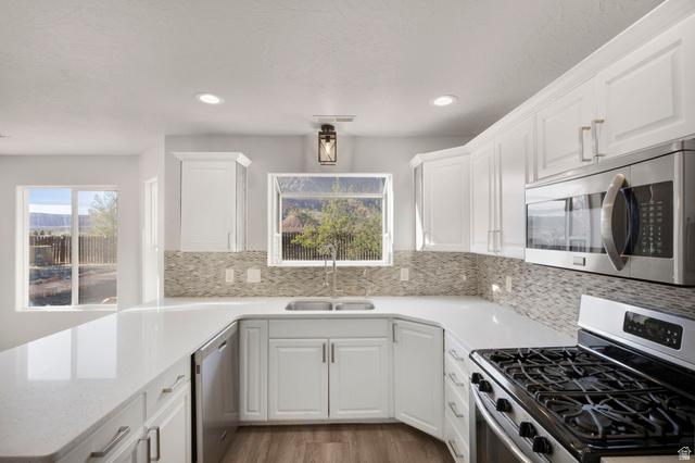 1440 West 100 South Virgin, UT 84779 - Photo 13 of 45 U-shaped kitchen featuring white cabinetry, light-toned countertops, and a full tile backsplash