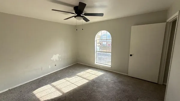 an empty room with a window and a ceiling fan