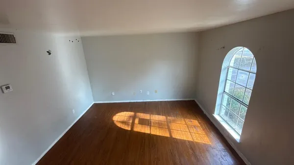 an empty room with wooden floor and windows