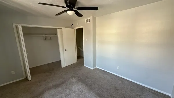 an empty room with closet and a ceiling fan