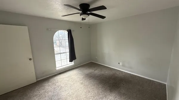 an empty room with a window and a fan