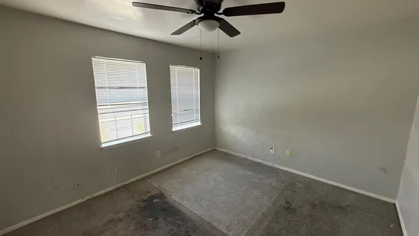 an empty room with a ceiling fan and windows
