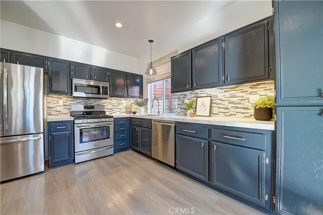 a kitchen with stainless steel appliances granite countertop a refrigerator a sink dishwasher a stove and a microwave oven